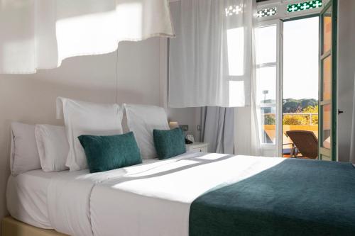 a bedroom with a large white bed with green pillows at 1881 Hotel Balneario Vichy Catalan in Caldes de Malavella