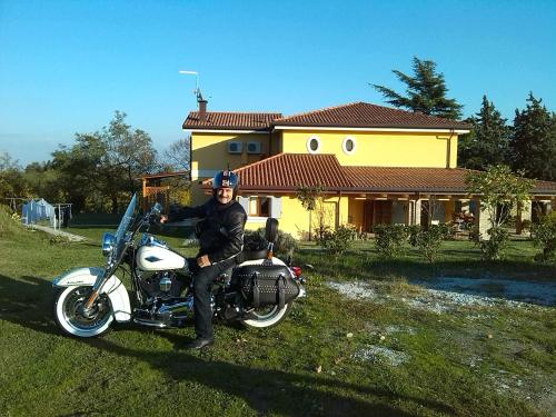 a man sitting on a motorcycle in front of a house at Bed & Breakfast Montesterlino in Cesena