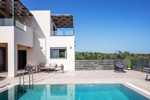 a house with a swimming pool and a patio at Garde Villa, with Private Pool, BBQ & Playground, By ThinkVilla in Roumelí