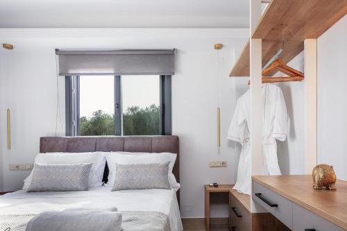 a bedroom with a bed with white sheets and a window at Garde Villa, with Private Pool, BBQ & Playground, By ThinkVilla in Roumelí