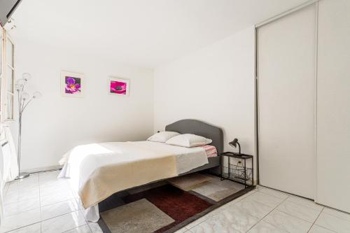 - une chambre blanche avec un lit et deux photos sur le mur dans l'établissement 2 Pièces cœur Vieux Nice avec stationnement, à Nice