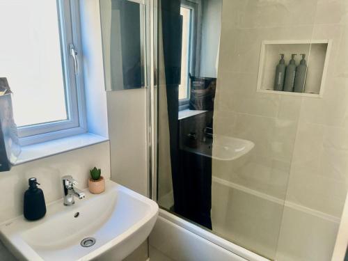 a white bathroom with a shower and a sink at Spacious 4-Bed House Close to City Centre in Wolverhampton