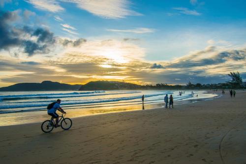 a man riding a bike on the beach at sunset at Chez Pitu Praia Hotel in Búzios