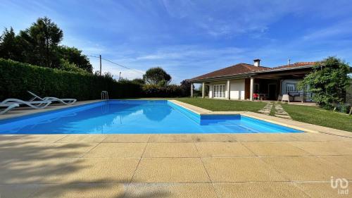 a blue swimming pool in front of a house at Casa rua do Capitão in Póvoa de Lanhoso