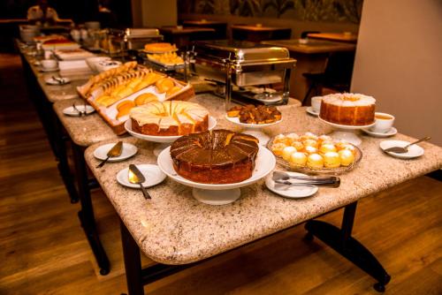 un lungo tavolo pieno di diversi tipi di torte e dessert di Luix Londrina Flat Hotel , 707, QS completo a Londrina
