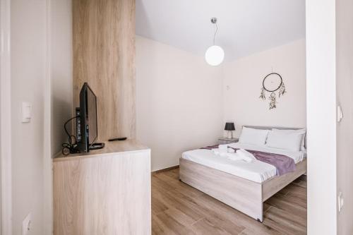 a white bedroom with a bed and a tv at CityView 2 fully equipped apt by Hospi in Heraklio Town