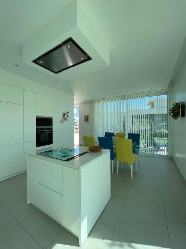 Casa Papoila في ألبوفيرا: مطبخ فيه دواليب بيضاء وكراسي صفراء