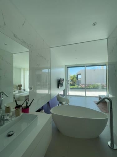 Casa Papoila في ألبوفيرا: حمام أبيض مع حوض استحمام ومغسلة