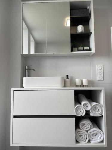 La salle de bains blanche est pourvue d'un lavabo et de serviettes. dans l'établissement Appartement T3 en centre-ville de Thonon-Les-Bains, à Thonon-les-Bains