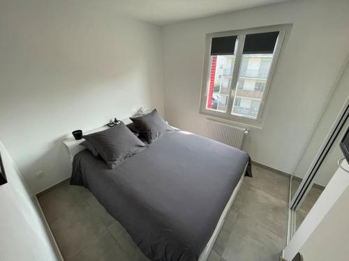 un lit dans une chambre blanche avec une fenêtre dans l'établissement Appartement T3 en centre-ville de Thonon-Les-Bains, à Thonon-les-Bains