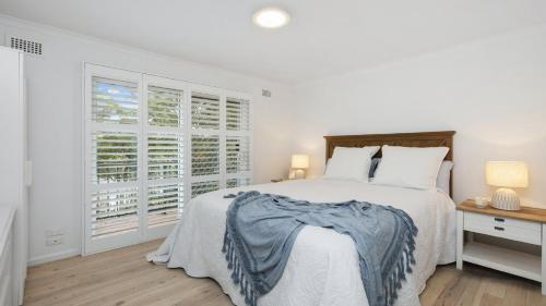 a white bedroom with a bed and a window at Short Walk To Beautiful Copacabana Beach & Lagoon in Copacabana