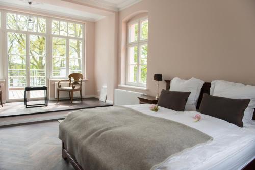 a white bedroom with a large bed and windows at Herrenhaus Röddelin in Templin