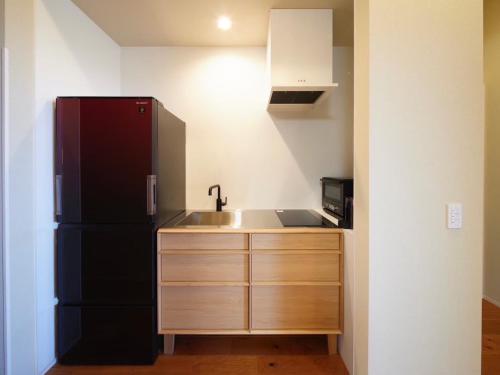 a kitchen with a black refrigerator and a sink at Doggy's Izujogasaki in Ito