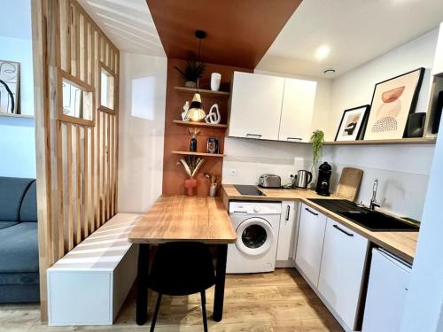une petite cuisine avec une table et un lave-linge. dans l'établissement Zola 2pers Tv, à Nantes