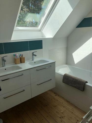 La salle de bains est pourvue d'un lavabo, d'une baignoire et d'une lucarne. dans l'établissement La Terre Ferme - Au cœur d'une ferme maraîchère, à Saint-Lunaire