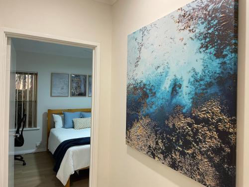 a bedroom with a painting on the wall next to a bed at Marina Upstairs Apartment & Marina Downstairs Retreat Beresford in Geraldton