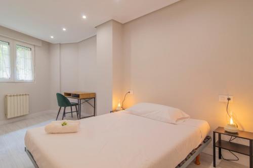 a bedroom with a white bed and a green chair at Apartamento Holidea Ayuntamiento de Santander in Santander