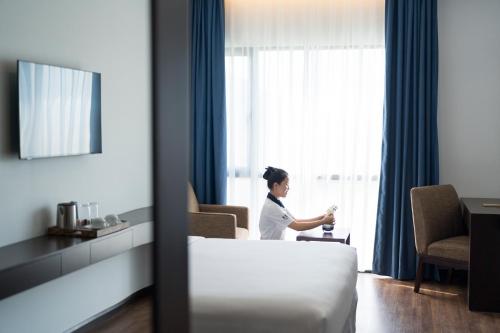 a woman in a hotel room looking out the window at TUI BLUE Tuy Hoa - Wellness & Retreat Hotel in Tuy Hoa