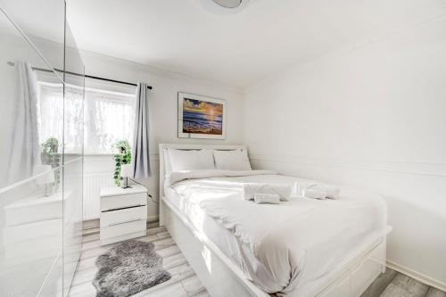 a white bedroom with a bed and a window at GuestReady - Urban Comfort near Wembley Stadium in London