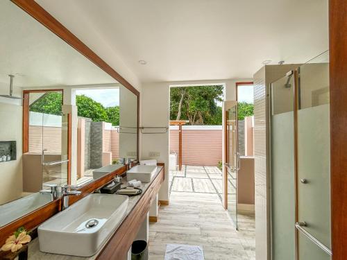 a bathroom with two sinks and a large mirror at Kudafushi Resort & Spa in Raa Atoll