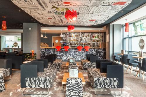 a restaurant with black and white chairs and a ceiling at ibis London Wembley in London