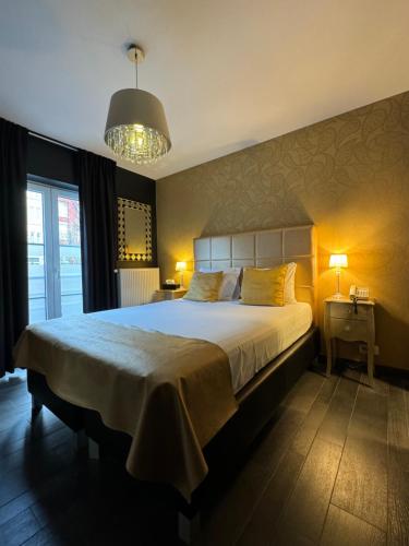 - une chambre avec un grand lit et un lustre dans l'établissement L'écrin des Vennes - Liège centre, à Liège