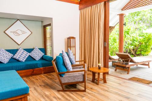 a living room with a blue couch and a patio at Kudafushi Resort & Spa in Raa Atoll