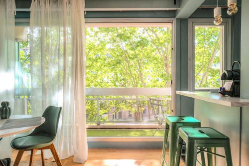 une cuisine avec une grande fenêtre et des tabourets verts dans l'établissement Appartement moderne proche Lyon 6ème, à Lyon
