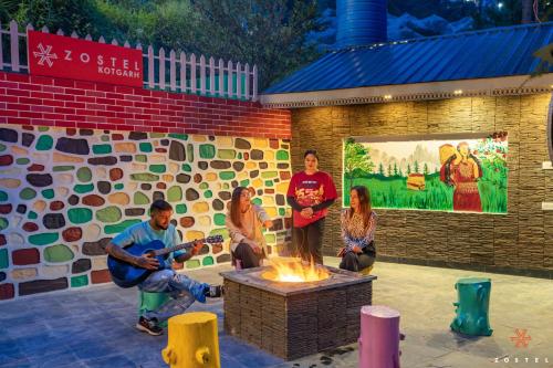 a group of people standing around a fire pit at Zostel Kotgarh, Narkanda in Kotgarh