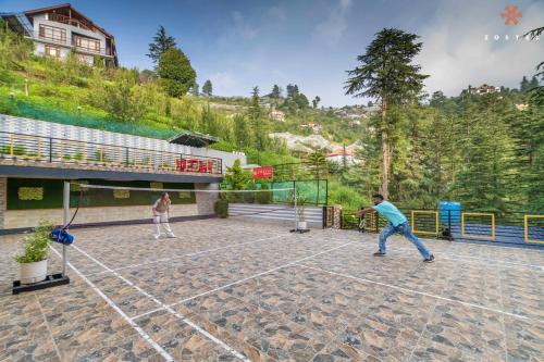two people playing tennis on a tennis court at Zostel Kotgarh, Narkanda in Kotgarh