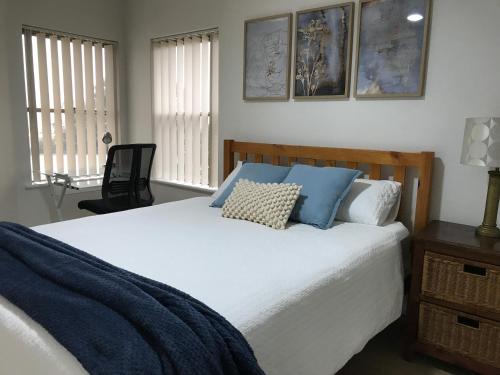 a bedroom with a large white bed with blue pillows at Marina Upstairs Apartment & Marina Downstairs Retreat Beresford in Geraldton