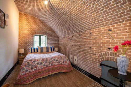 a brick room with a bed and a brick wall at Fort Vuren in Vuren