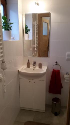 a white bathroom with a sink and a mirror at Apartament Cassino in Sopot