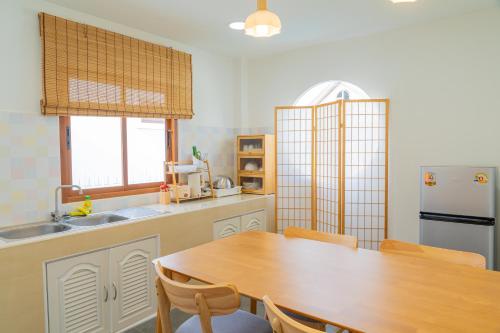 a kitchen with a wooden table and a refrigerator at Tenki Poolvilla surin in Surin