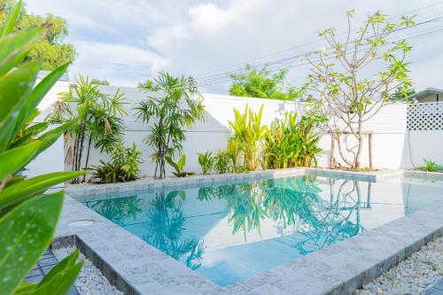 a swimming pool with plants in front of a white fence at Tenki Poolvilla surin in Surin