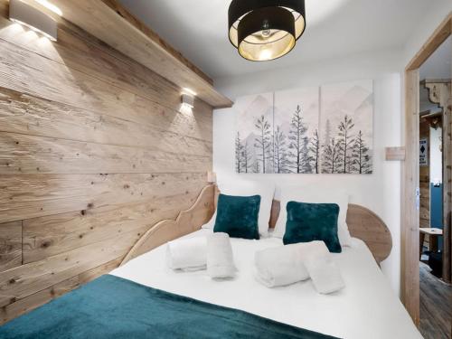 une chambre avec un grand lit blanc avec des oreillers verts dans l'établissement Appartement cosy aux pieds des pistes avec services inclus - FR-1-640-57, à Val Thorens