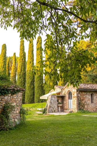 a stone building in the middle of a yard with trees at Borgo San Luigi in Monteriggioni