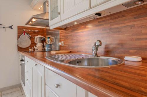 une cuisine avec un évier et un plan de travail en bois dans l'établissement Appt vue Mer 5 min centre et plage, à Saint-Raphaël