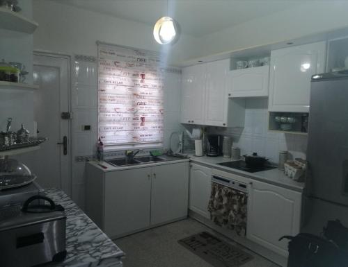 a kitchen with white cabinets and a sign on the wall at Joli appartement vue sur la mer in Sousse