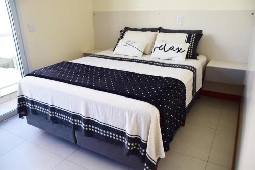 a bed with black and white sheets and pillows at Apartamento a beira mar completo com churrasqueira in Florianópolis