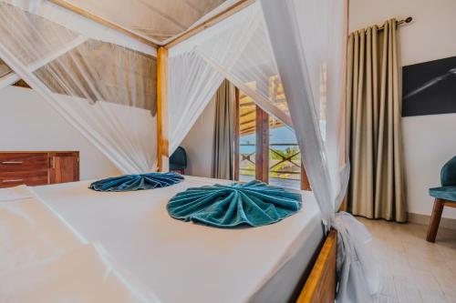 a bedroom with a bed with blue pillows on it at Zaria Garden Bungalows in Pwani Mchangani