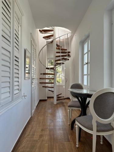 a dining room with a table and a spiral staircase at Hotel Miranda in Hydra
