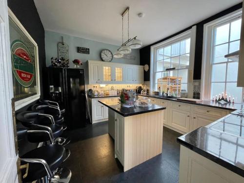 a large kitchen with white cabinets and a black refrigerator at Uplands House Tewkesbury in Tewkesbury