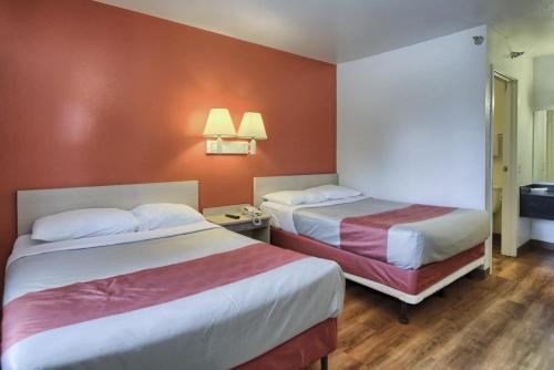 two beds in a hotel room with orange walls at Motel 6-New Cumberland, PA - Harrisburg - Hershey South in New Cumberland