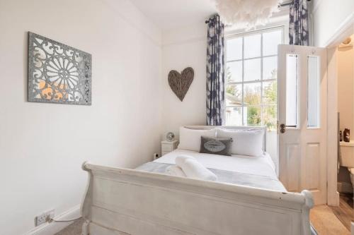 a bedroom with a bed with white sheets and a window at Uplands House Tewkesbury in Tewkesbury