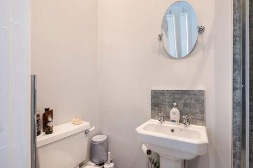 a white bathroom with a sink and a mirror at Uplands House Tewkesbury in Tewkesbury