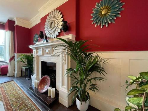 a living room with a fireplace and a red wall at Uplands House Tewkesbury in Tewkesbury