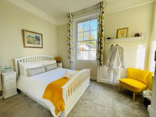 a bedroom with a white bed and a yellow chair at Uplands House Tewkesbury in Tewkesbury