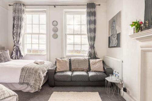 a bedroom with a bed and a leather couch at Uplands House Tewkesbury in Tewkesbury