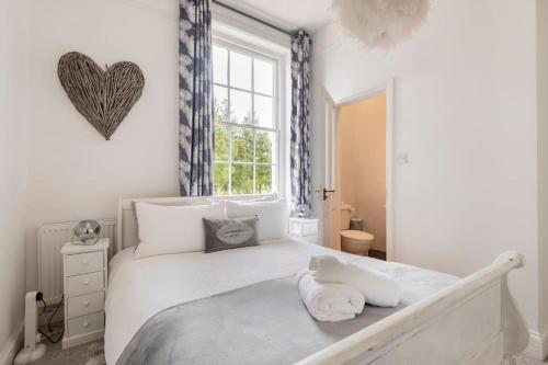 a white bedroom with a large bed and a window at Uplands House Tewkesbury in Tewkesbury